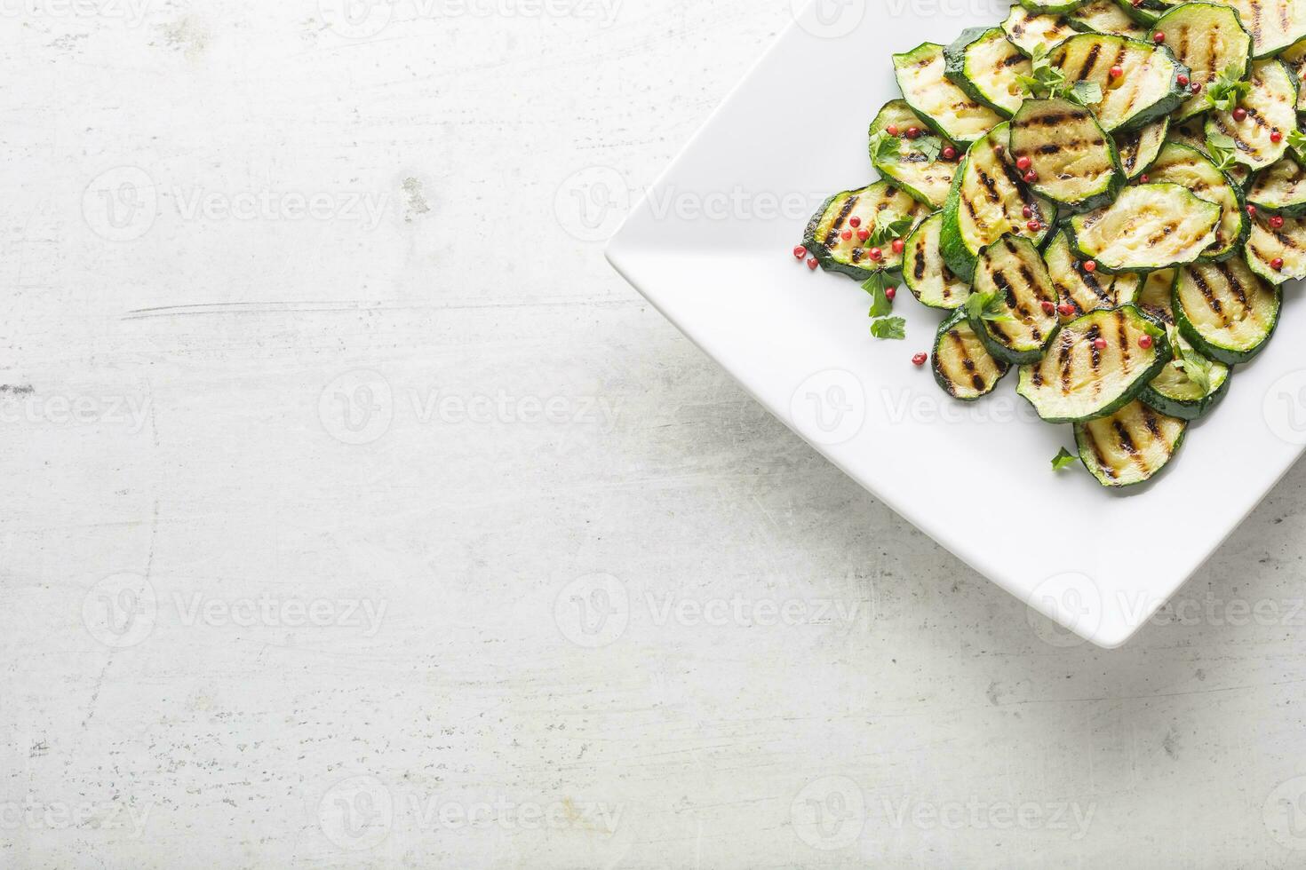 Zucchini. Grilled zucchini with red spice on white plate photo