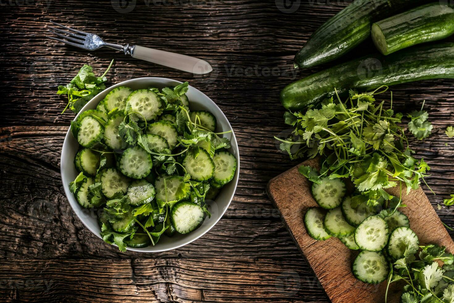 rebanado Pepino en un plato con perejil hierba en rústico roble madera. foto