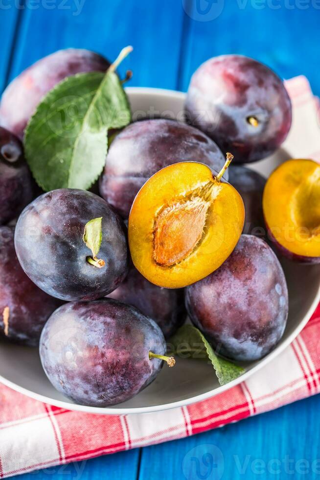 Plums. Fresh juicy plums in a bowl on a wooden or concrete board photo