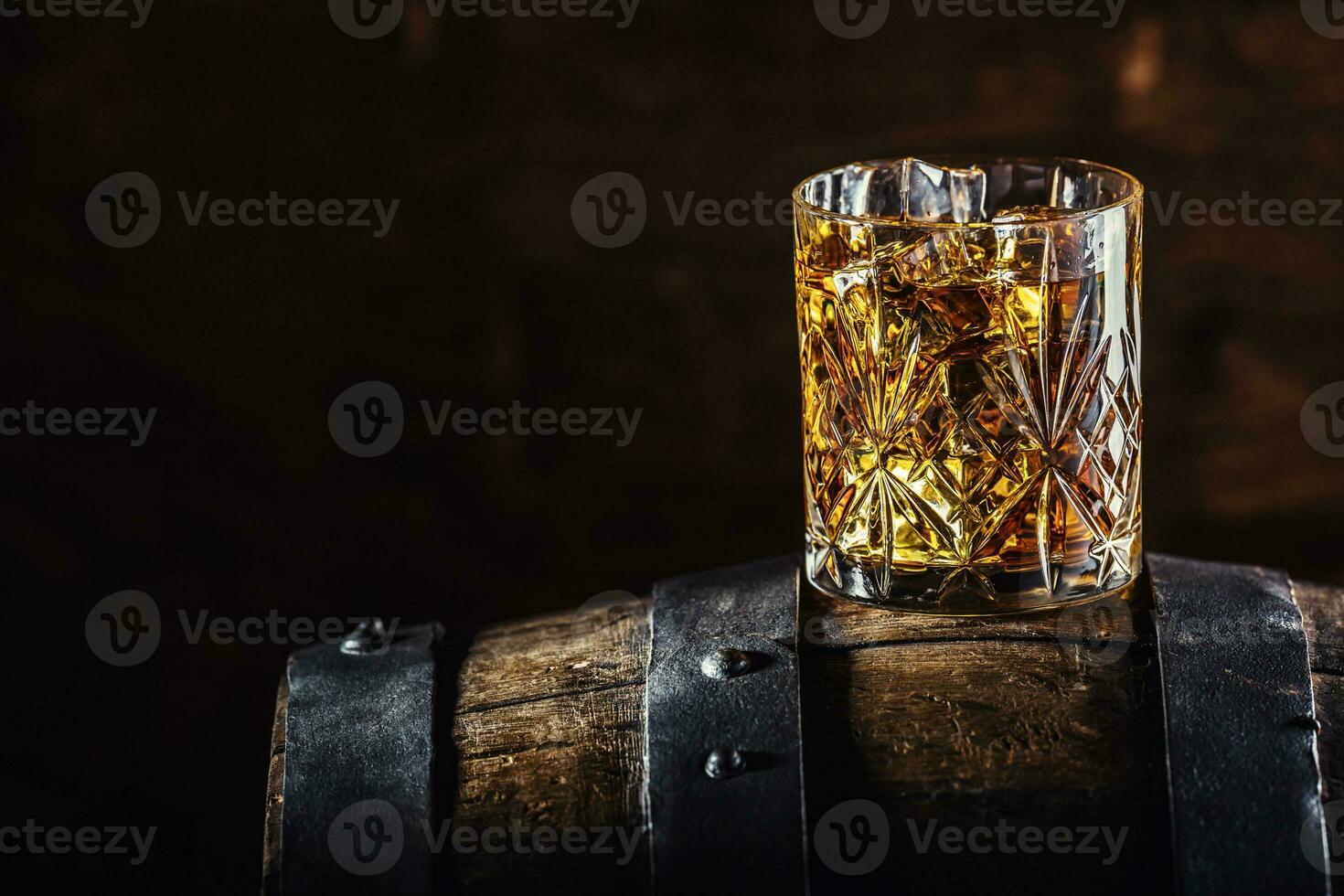 A glass of whiskey on an old wooden barrel photo