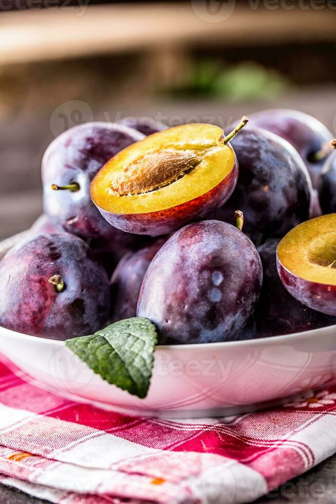 Plums. Fresh juicy plums in a bowl on a wooden or concrete board photo