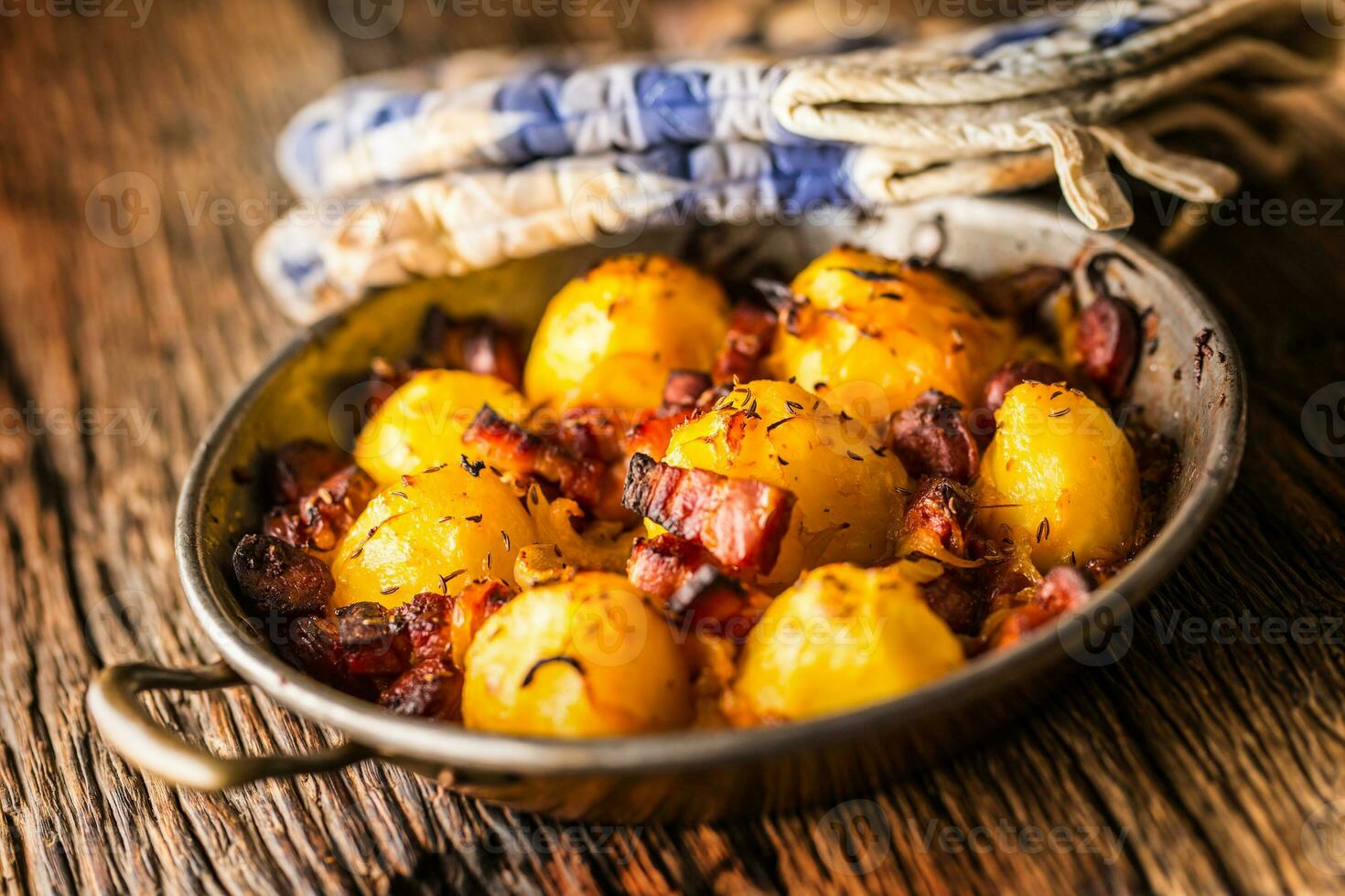 Potatoes. Roasted potatoes with bacon onion and sausages on old oak table photo