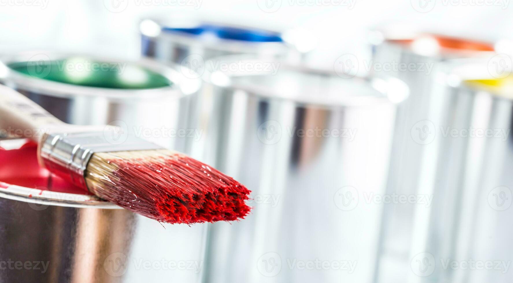 Close-up brush with red color lying on paint can. photo