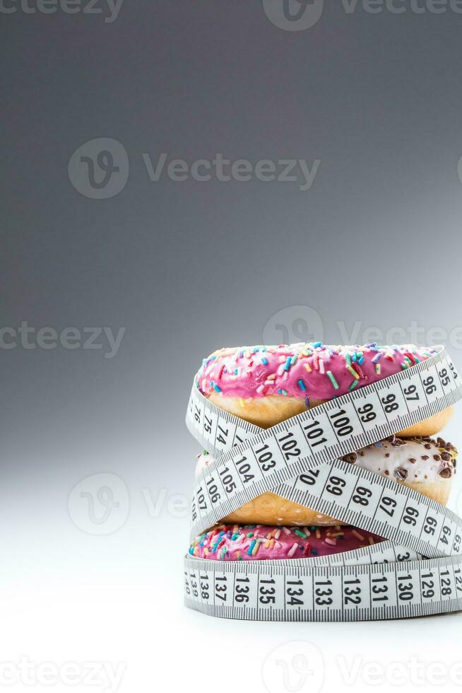 Three colorful donuts wrapped in a tailors measuring tape photo