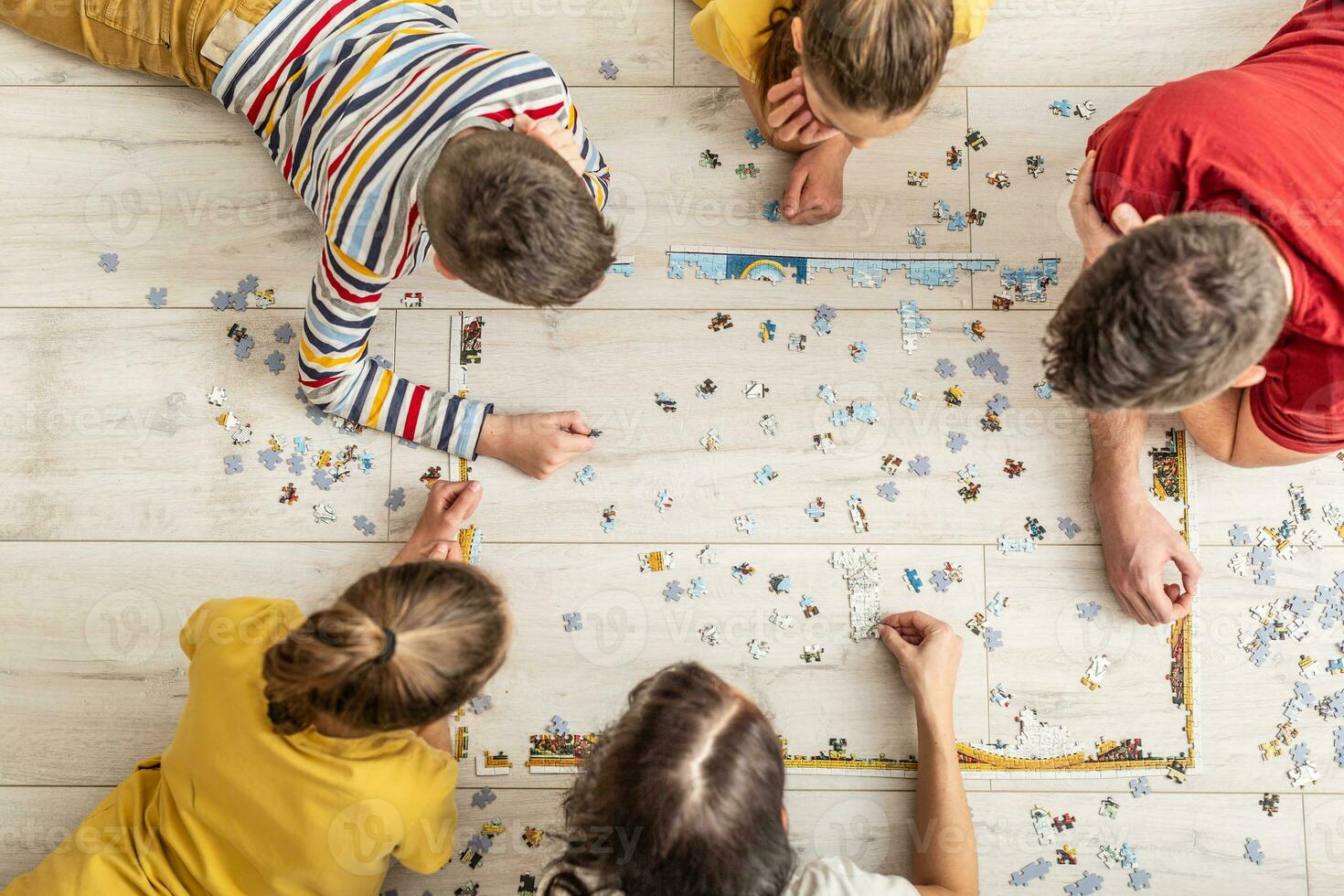 Top view of a family assembling puzzle on the floor at home photo