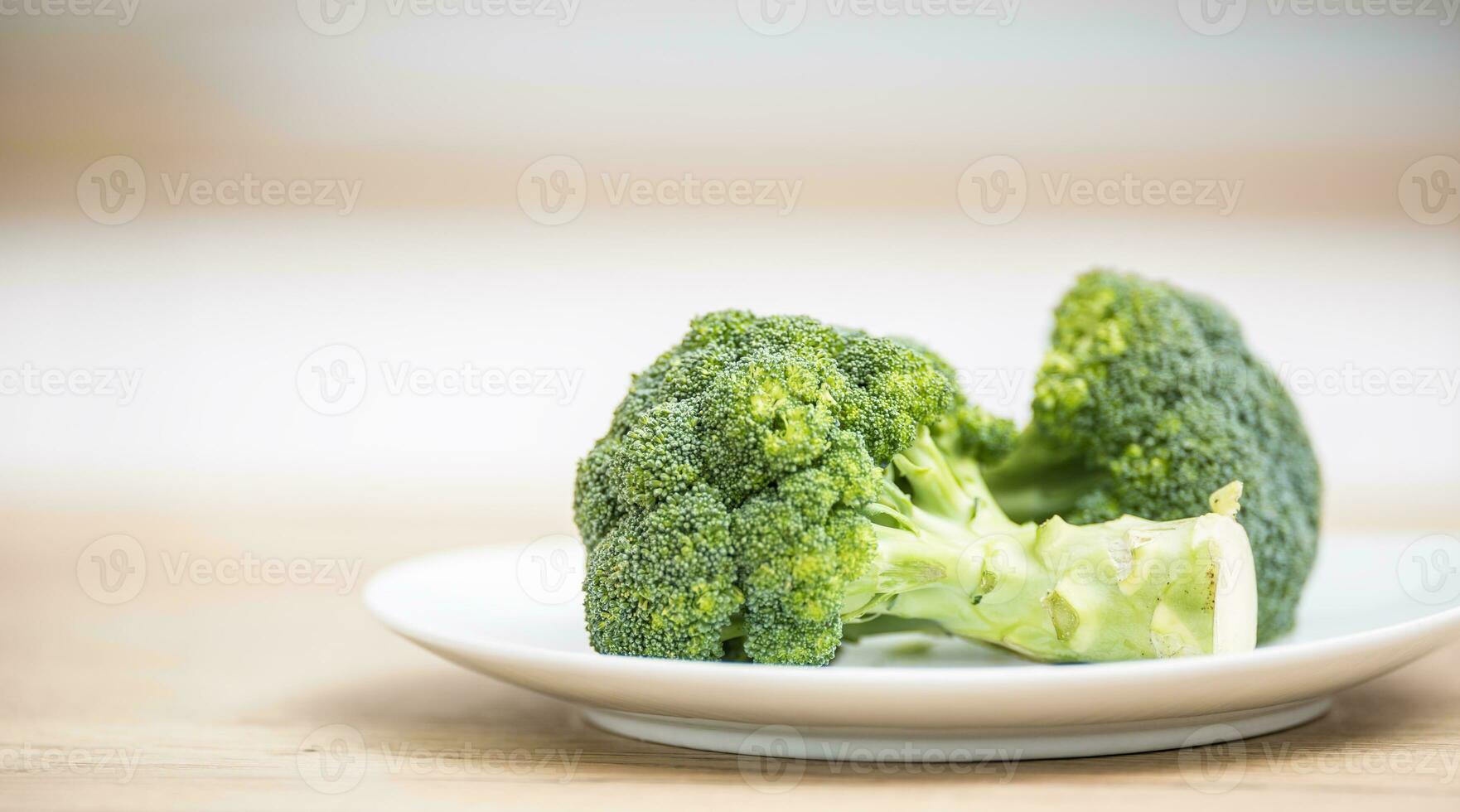 Fresh green broccoli in plate on kitchen wooden board photo