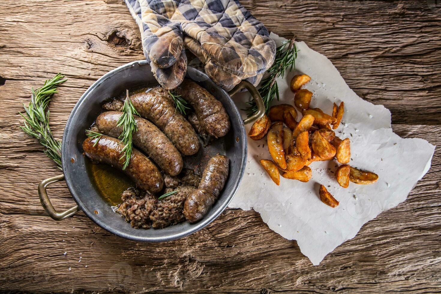 Sausages.Roasted pork sausage in a pan with potatoes and rosemary. photo