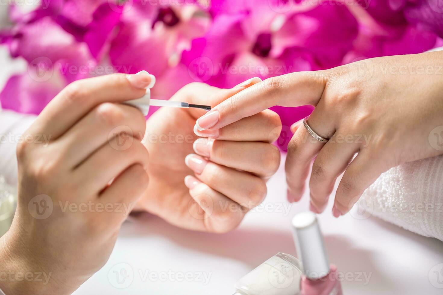 Manicure specialist painting woman gel nail. Art - French manicure photo