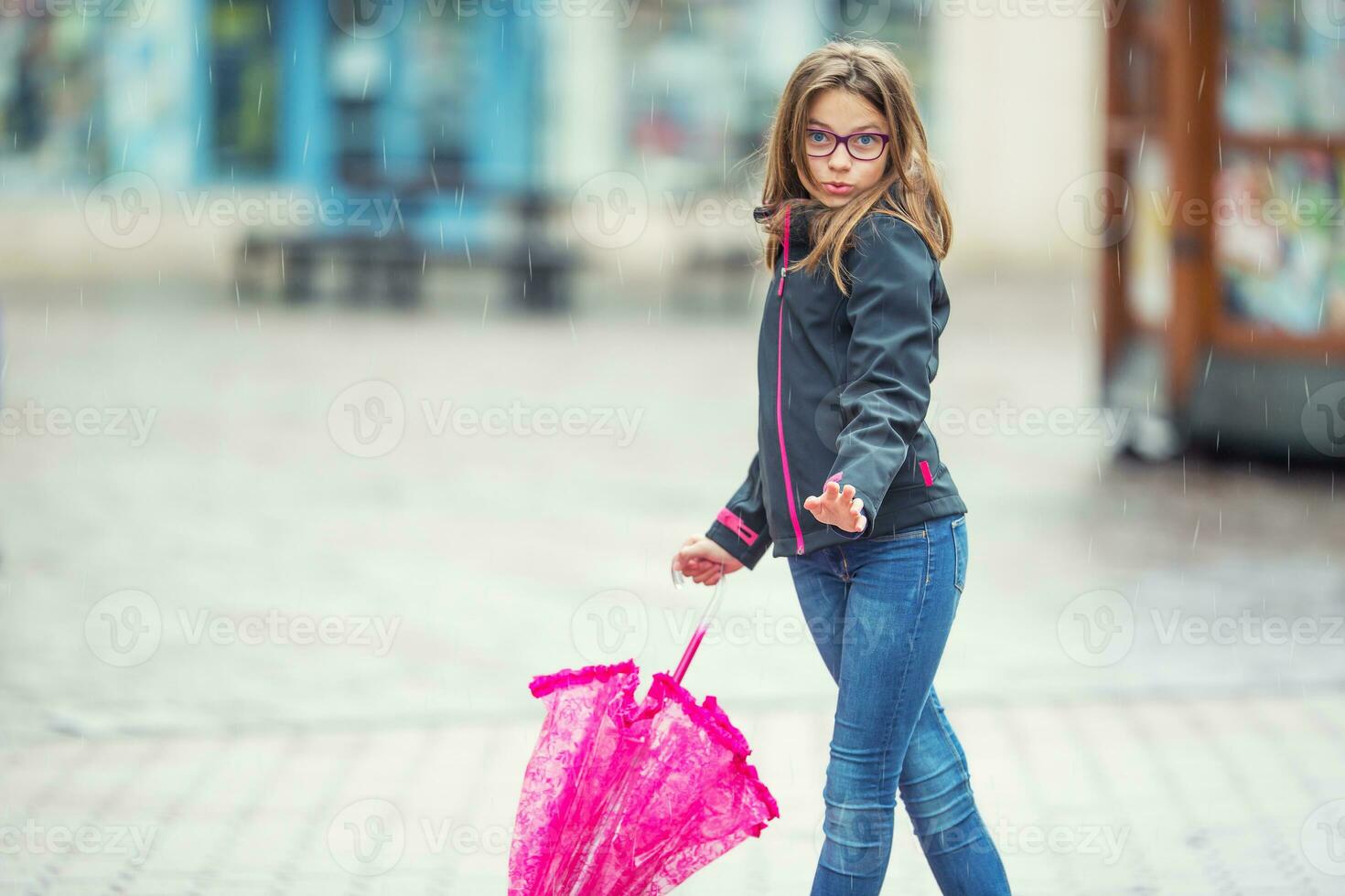 Portrait of happy beautiful young pre-teen girl with pink umbrella under rain. photo