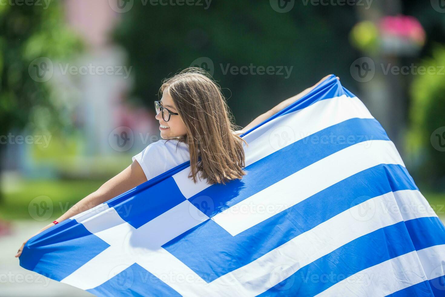 Happy girl tourist walking in the street with greece flag photo
