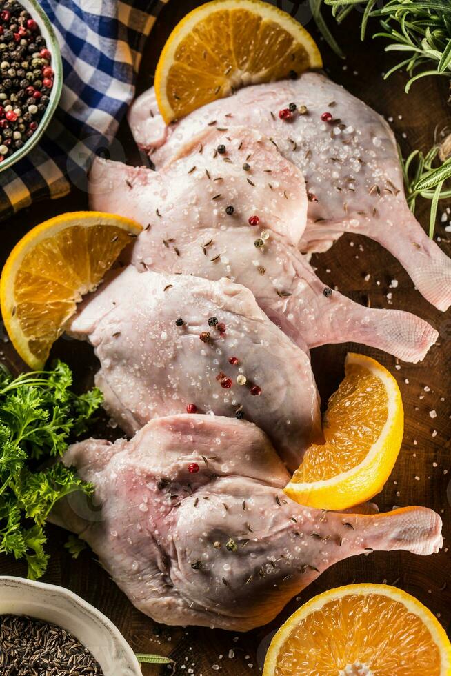 Top of view raw duck legs with oranges and herbs. photo