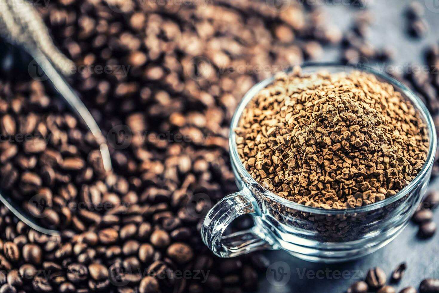 Granules of instant coffee in glass cup and coffee beans. photo