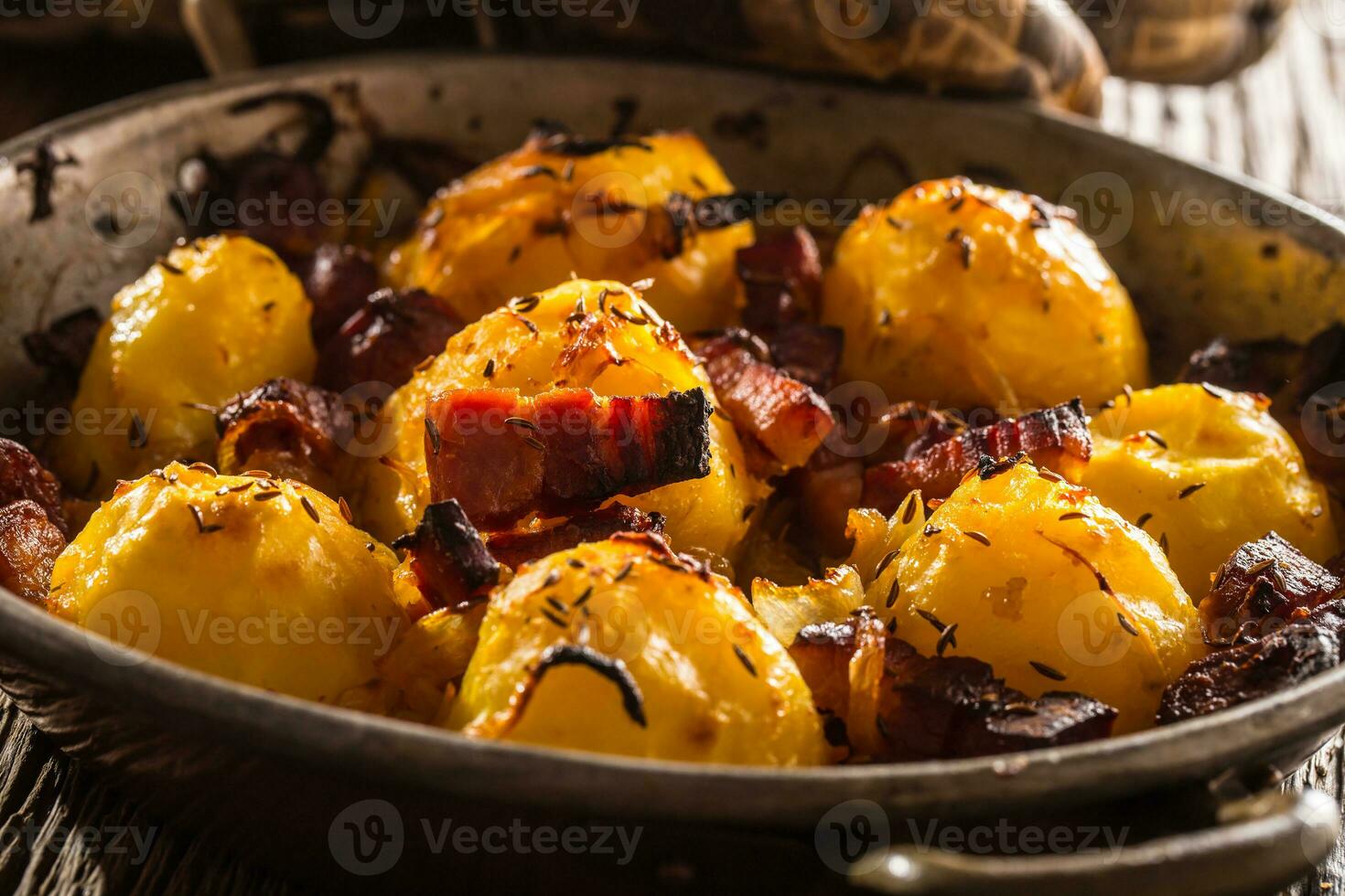 papas. asado patatas con tocino cebolla y salchichas en antiguo roble mesa foto