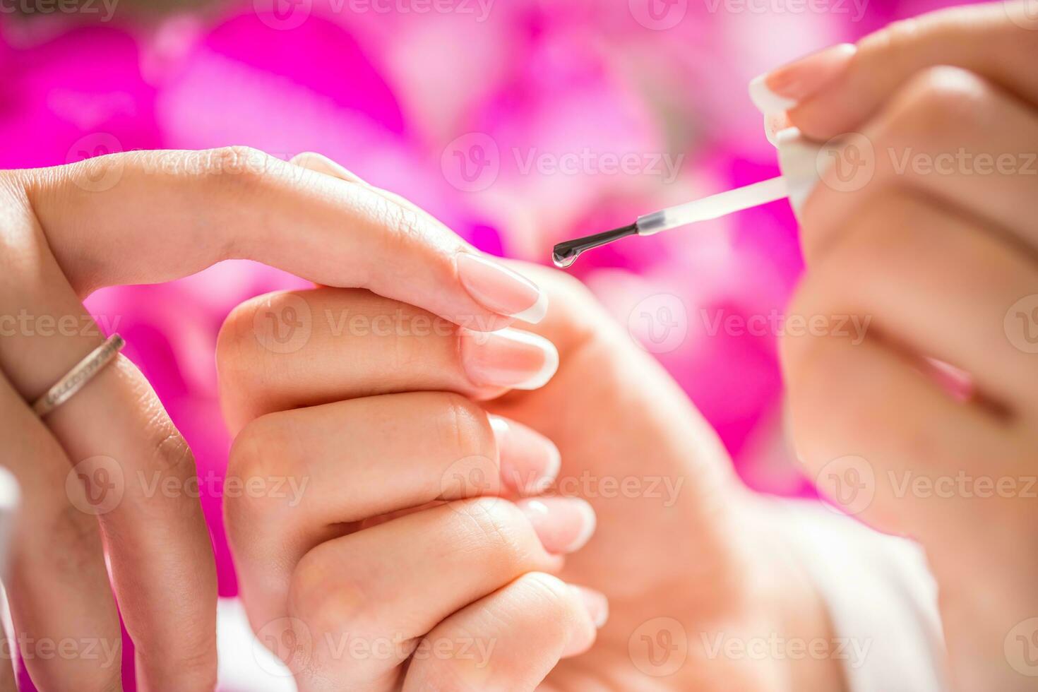 Manicure specialist painting woman gel nail. Art - French manicure photo