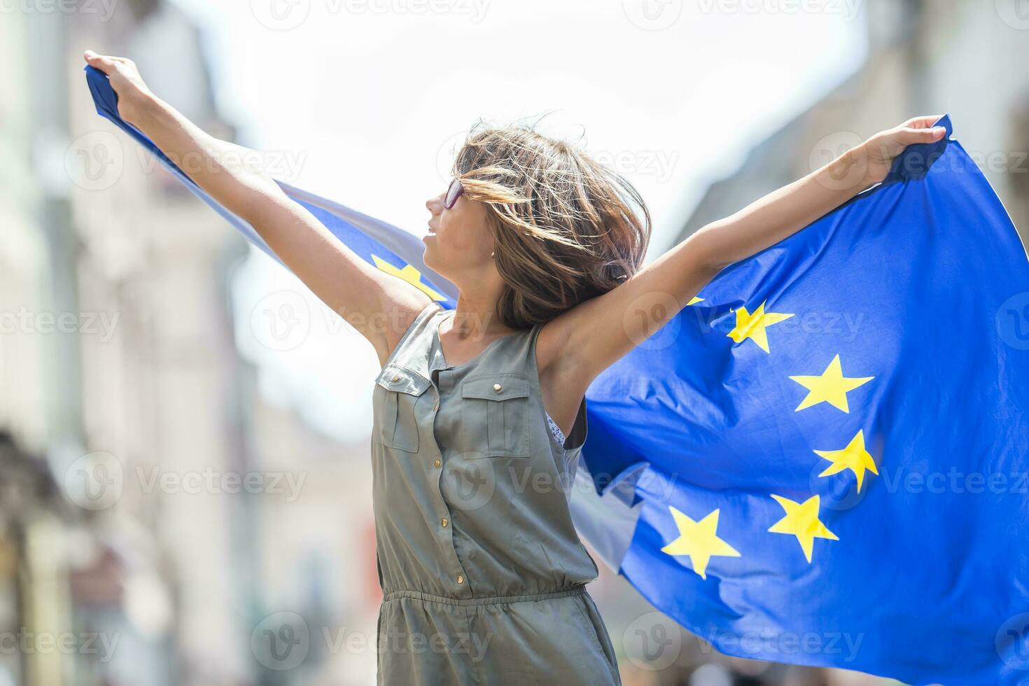 UE bandera. linda contento niña con el bandera de el europeo Unión. joven Adolescente niña ondulación con el europeo Unión bandera en el ciudad foto