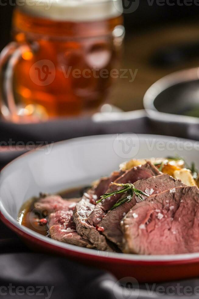 Sliced Beef tenderloin roasted steak potatoes rosemary and draft beer photo