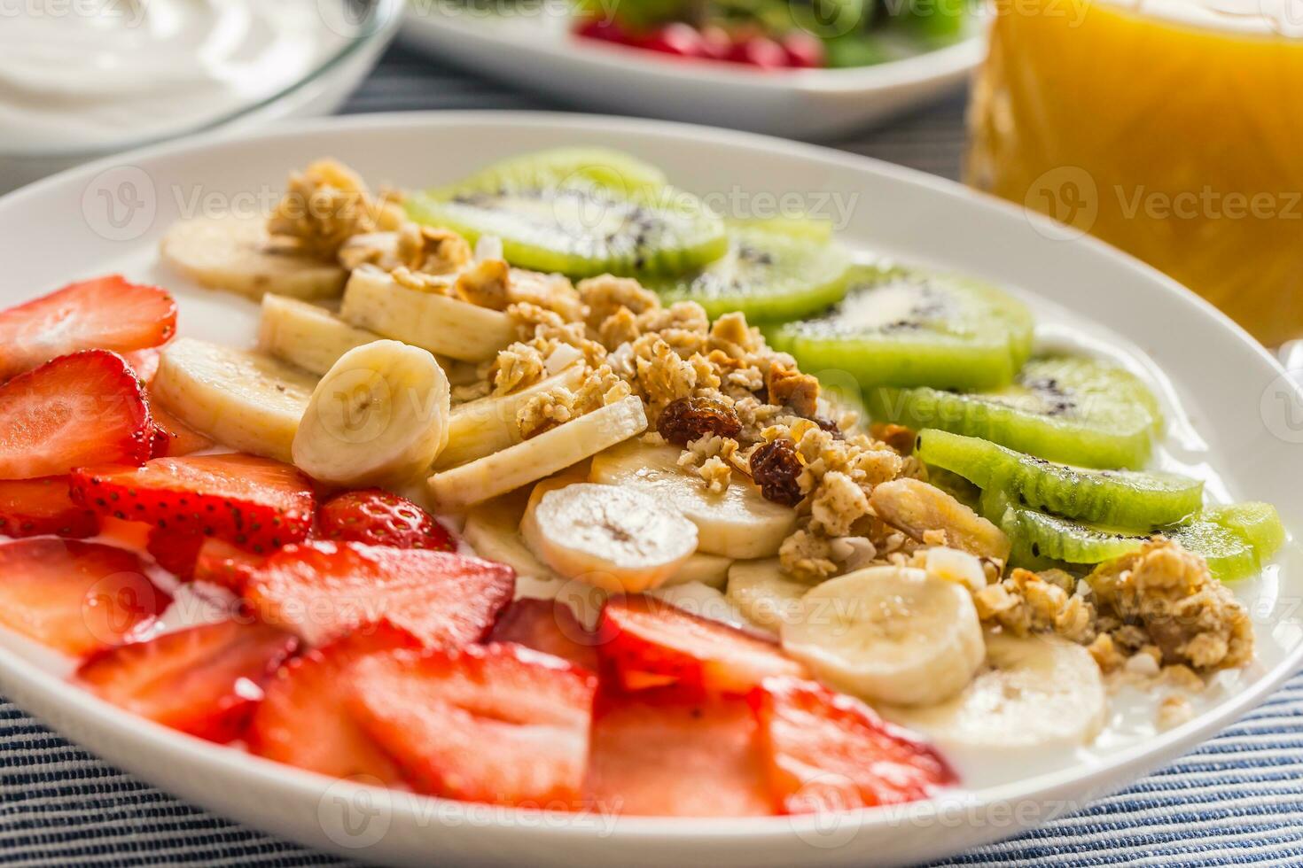 Healthy breakfast served with plate of yogurt muesli kiwi strawberries and banana photo