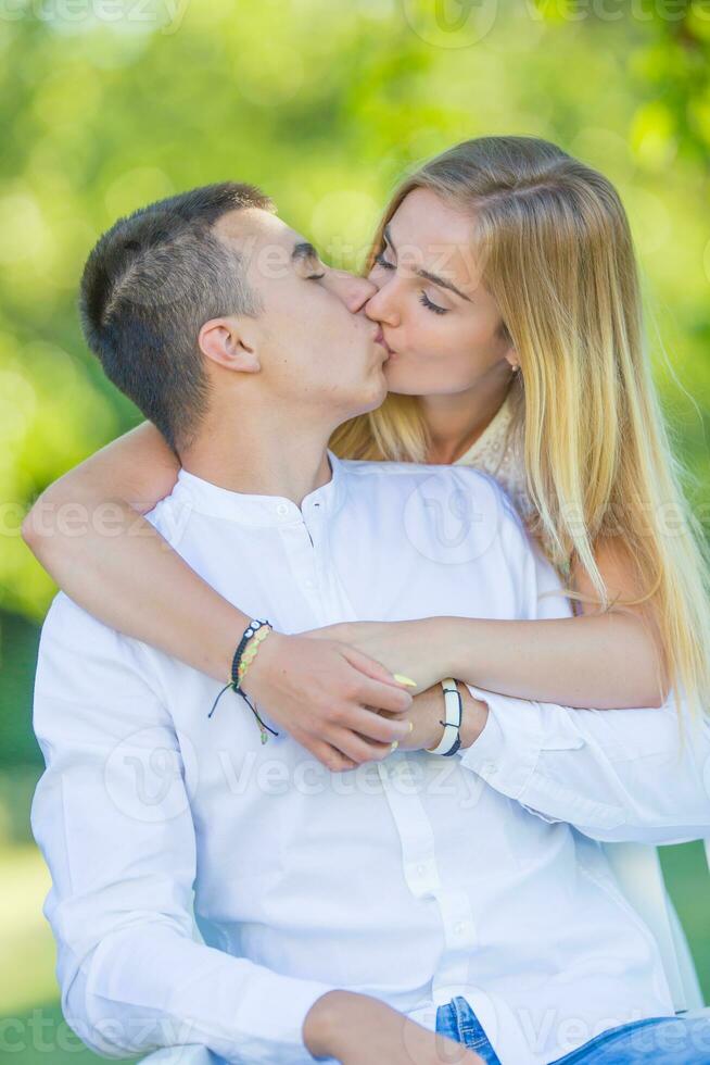 joven niña sorprendente su novio por un abrazo desde detrás y un Beso en labios mientras en un fecha en naturaleza foto