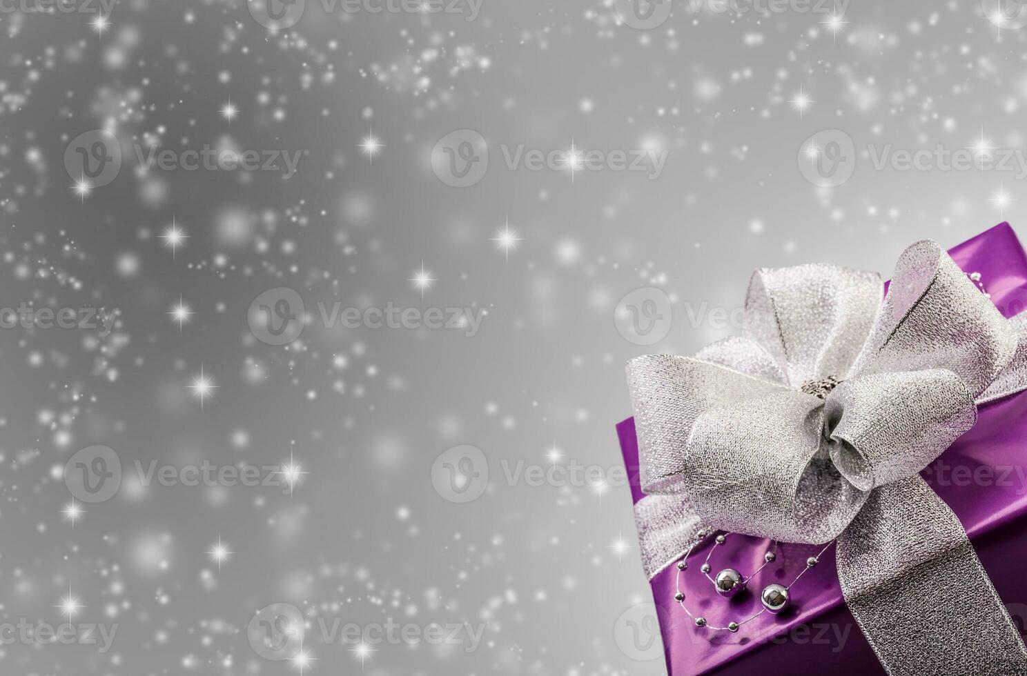 Christmas bokeh concept with purple present in the bottom right corner and illustrated snowflakes in the background photo