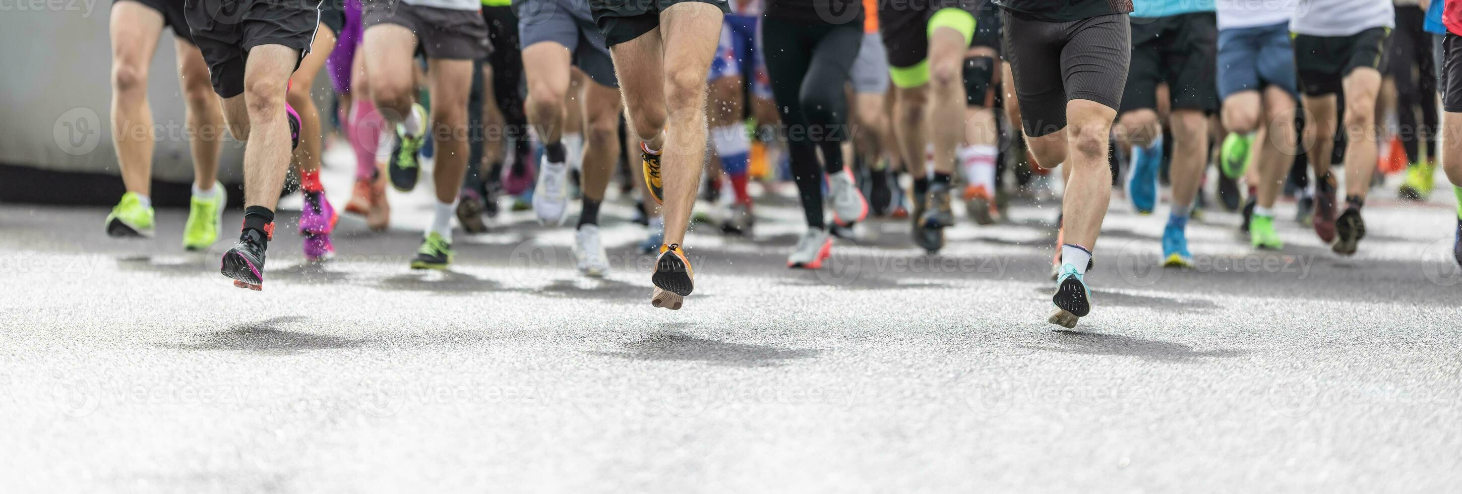 Runners in shorts and trainers start running a competition, with only their legs visible photo