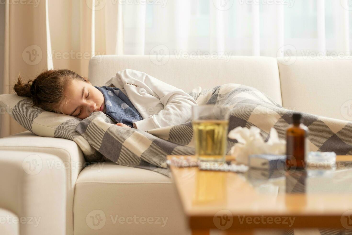 Sleeping young sick girl lying on a sofa with cold and high fever photo