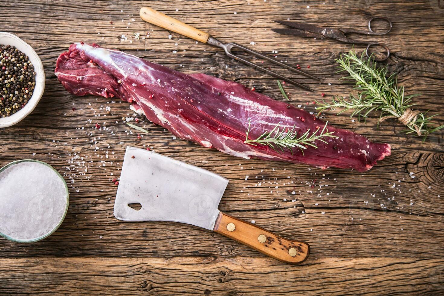 Raw beef meat. Raw beef tenderloin steak on a cutting board with rosemary pepper salt in other positions. photo