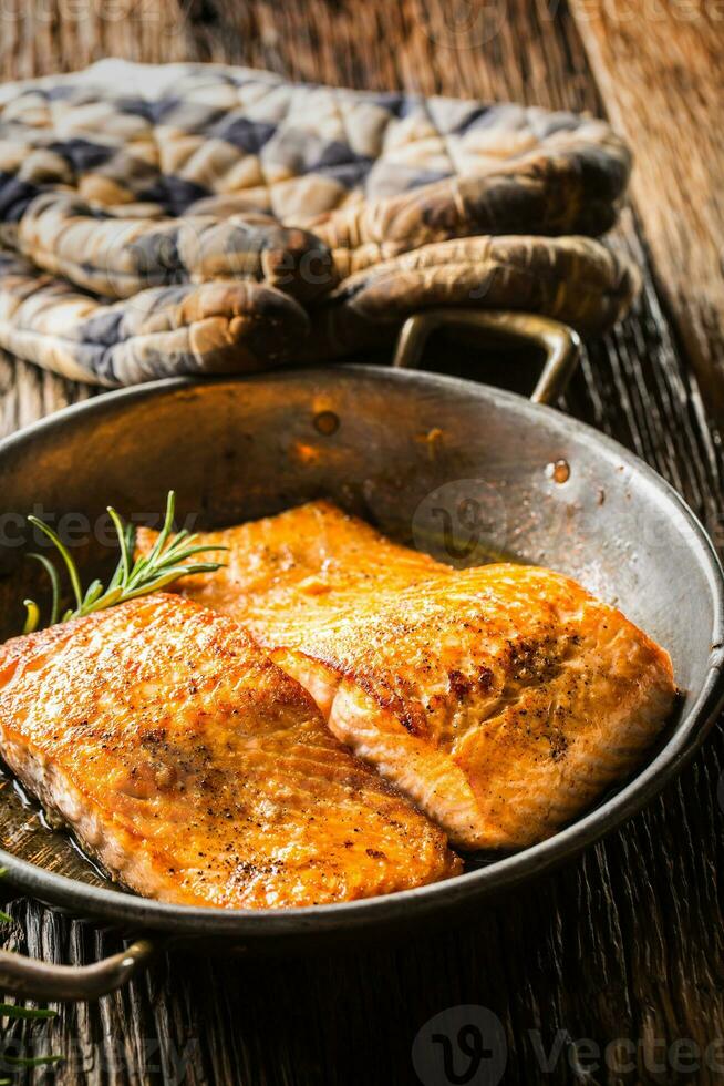 Salmon. Two juicy salmon steaks in roast pan with herb decoration on rustic oak table photo