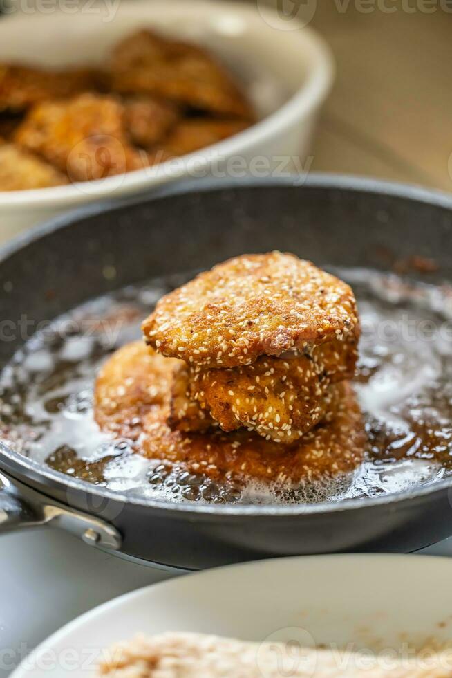 Schnitzels with sesame seeds in a frying pan photo