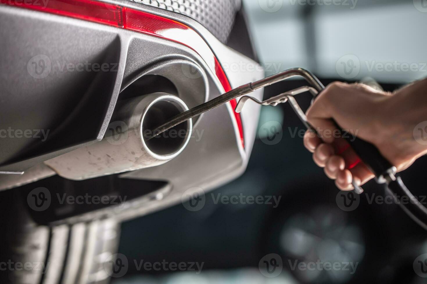 Measurement of exhaust emissions at the technical inspection station. A car repairman applies a probe to the exhaust photo