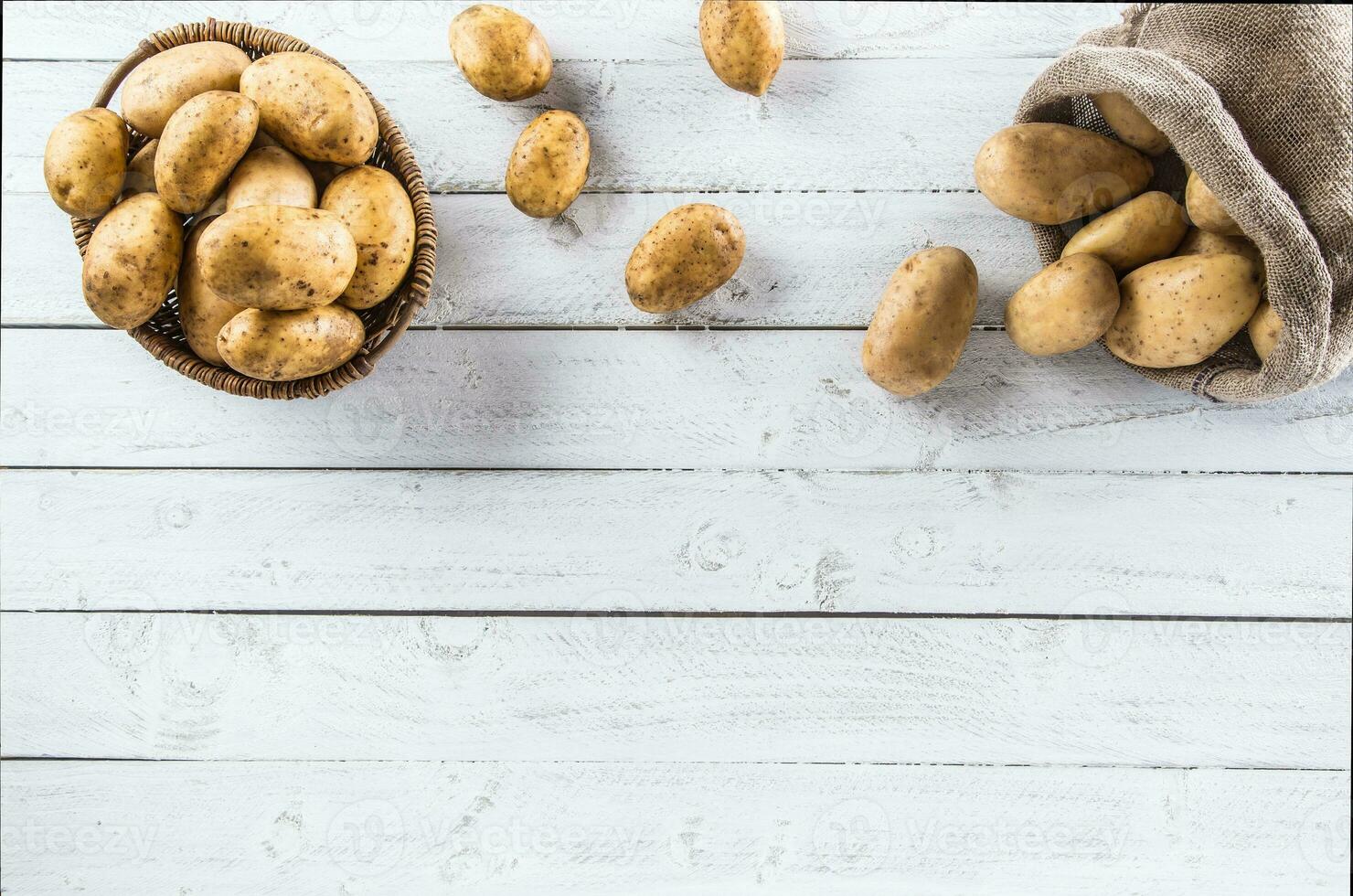 Ripe potatoes in burlap sack freely lying on board. photo