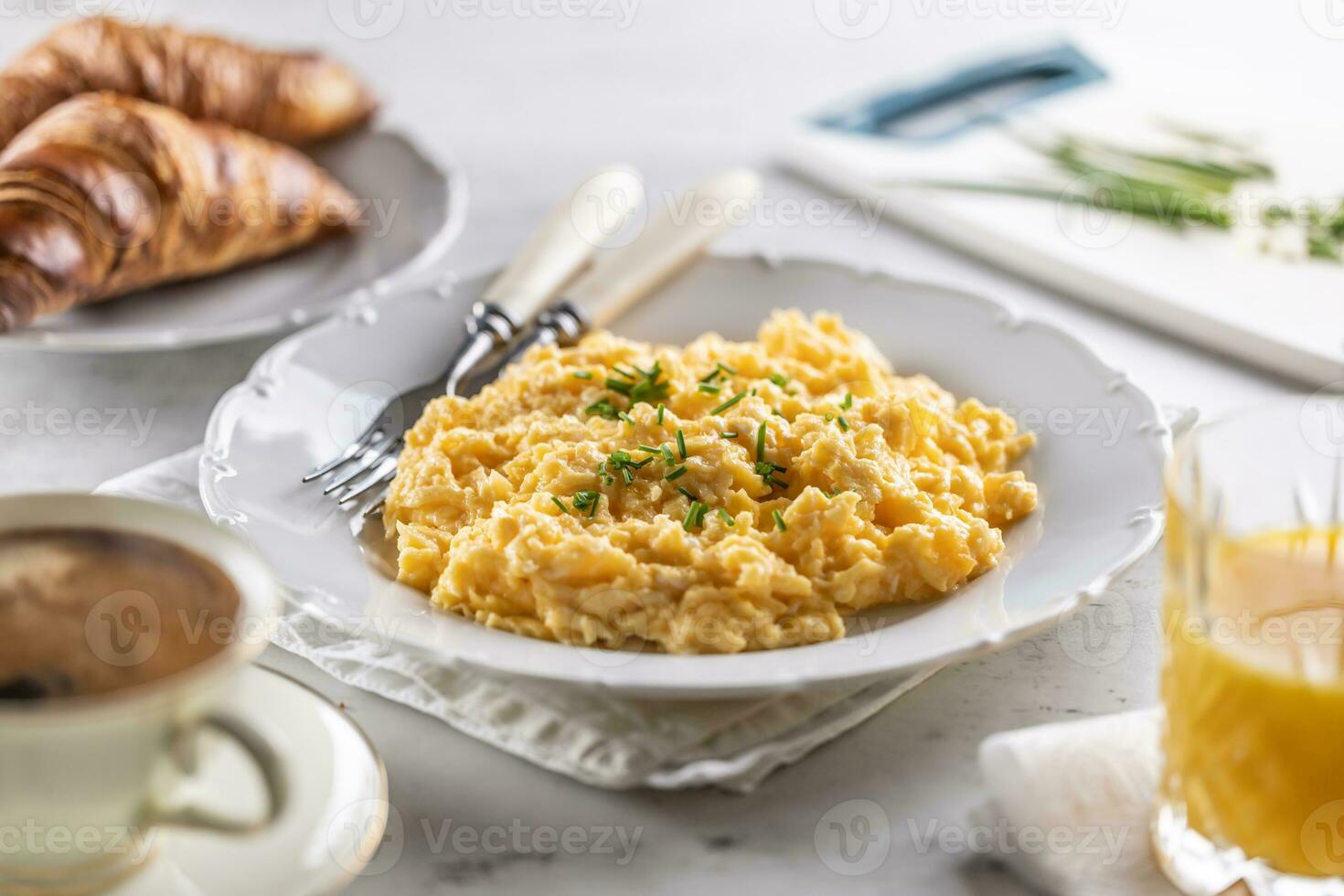 Breakfast served with a plate of scrambled eggs, croissants, orange juice and cofffee photo