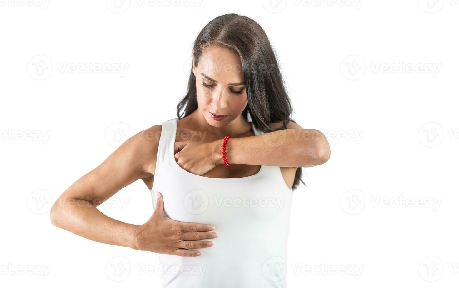 joven mujer checando su senos vistiendo un blanco parte superior y haciendo autoexamen a evitar cáncer. aislado antecedentes foto