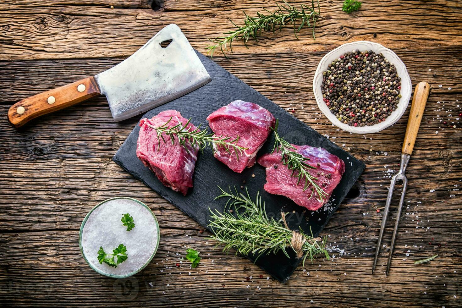 Raw beef meat. Raw beef tenderloin steak on a cutting board with rosemary pepper salt in other positions. photo