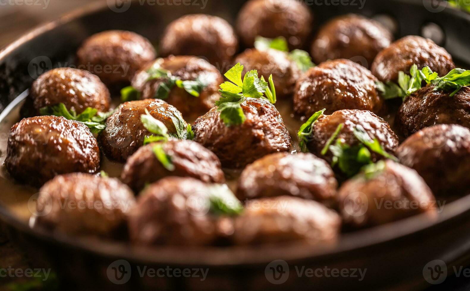 Detail of Swedish meatballs, kottbullar, in a pan topped with fresh parsley photo