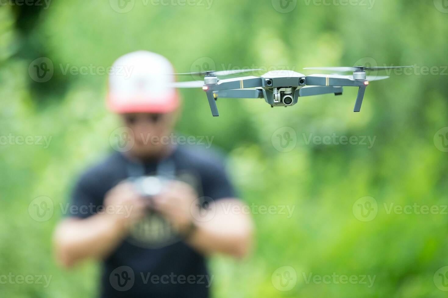 joven hombre participación remoto controlador y volador con zumbido en el parque foto