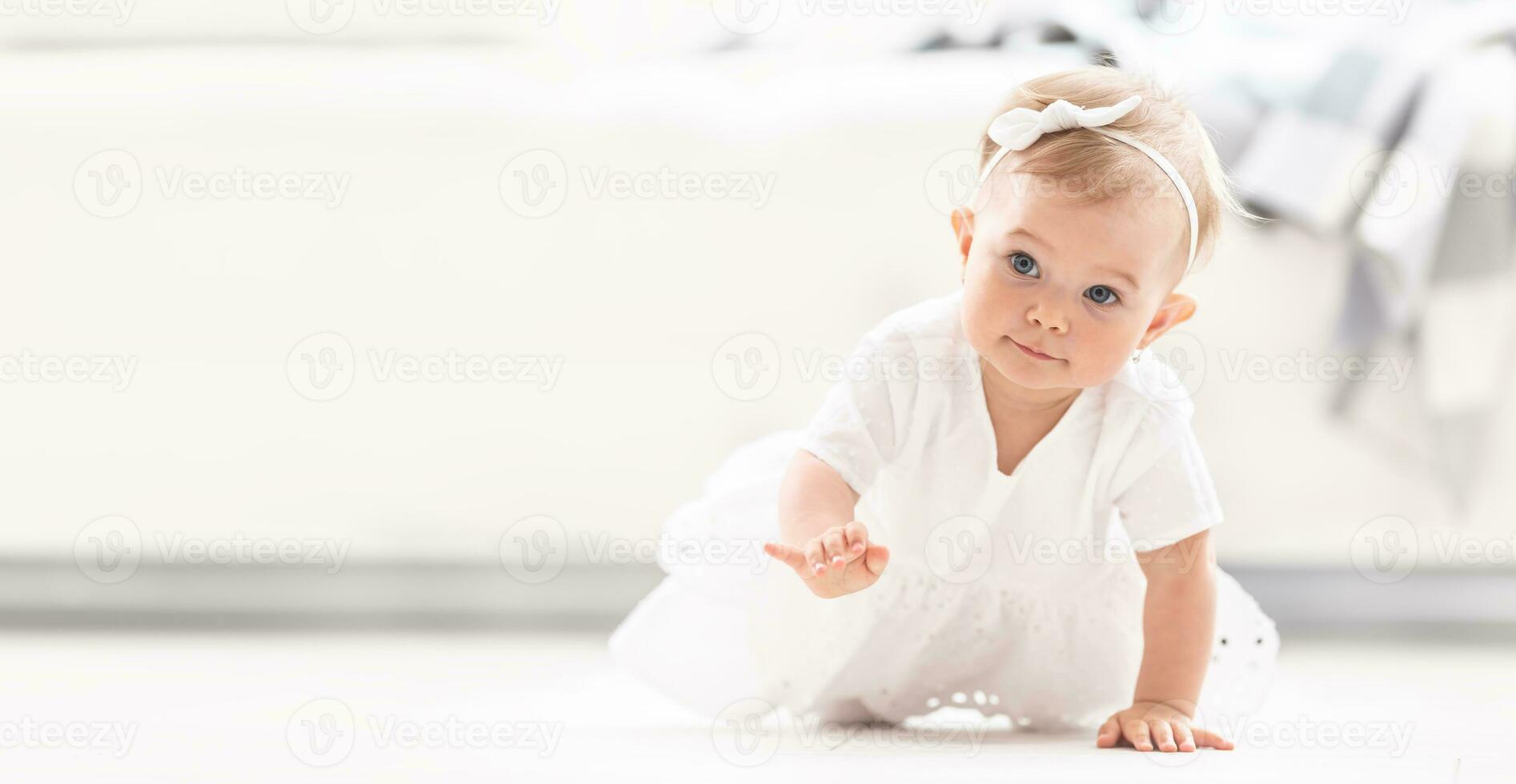 Satisfied small baby girl crawls at home with one hand raised off the floor photo