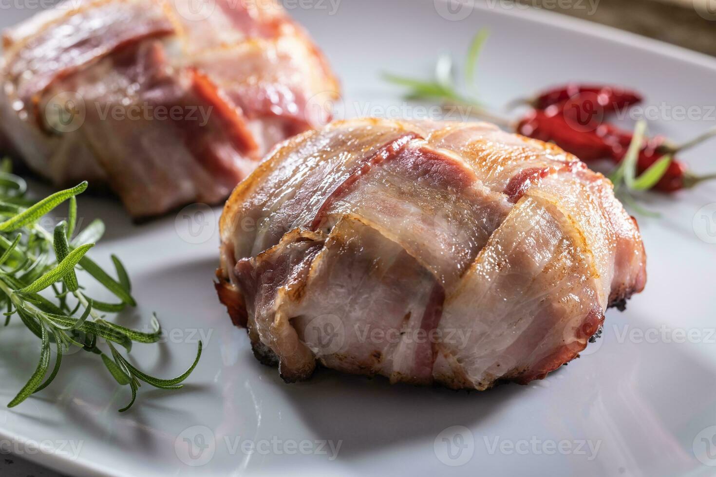 Crispy bacon wraps served on a plate with rosemary and chillies photo