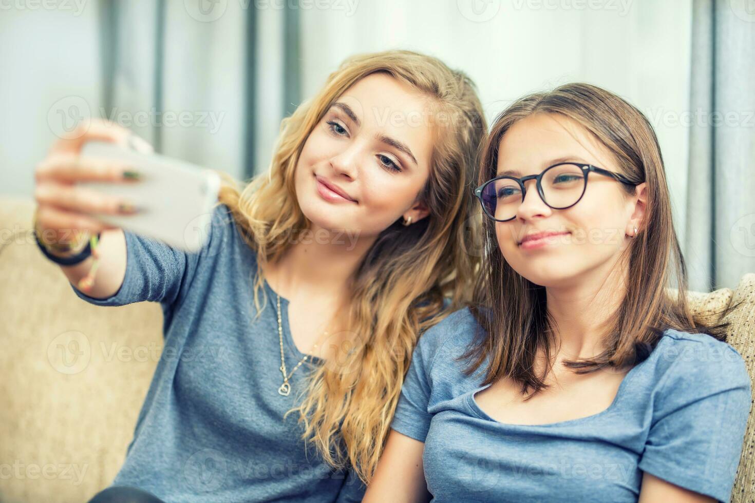 dos adolescente muchachas sonrisa y tomar un selfie juntos. foto