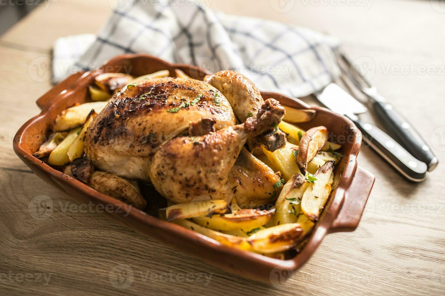 Roasted whole chicken with potatoes in baking dish. Tasty food a photo
