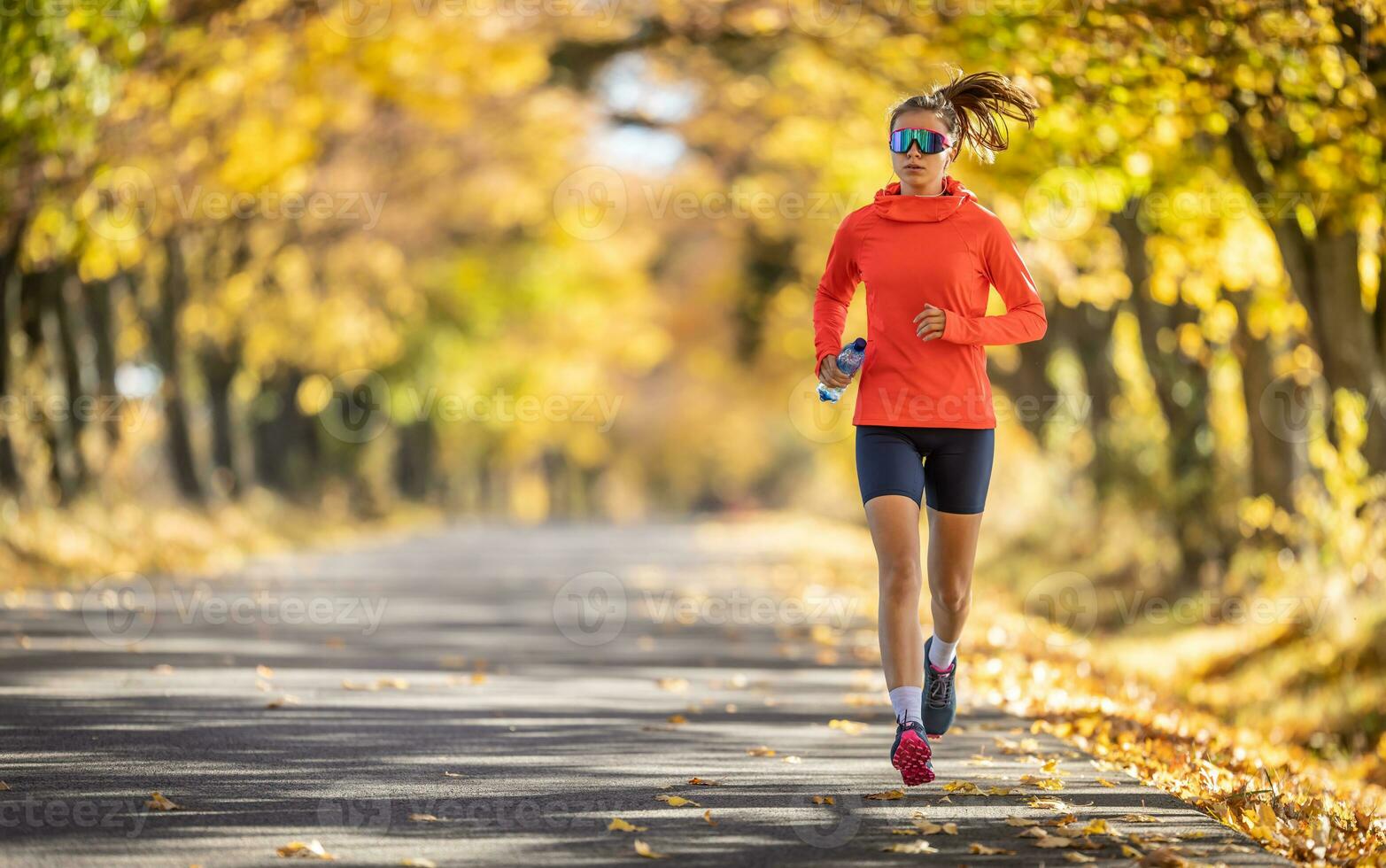 Young female athlete in sportswear runs in the park during warm indian summer photo