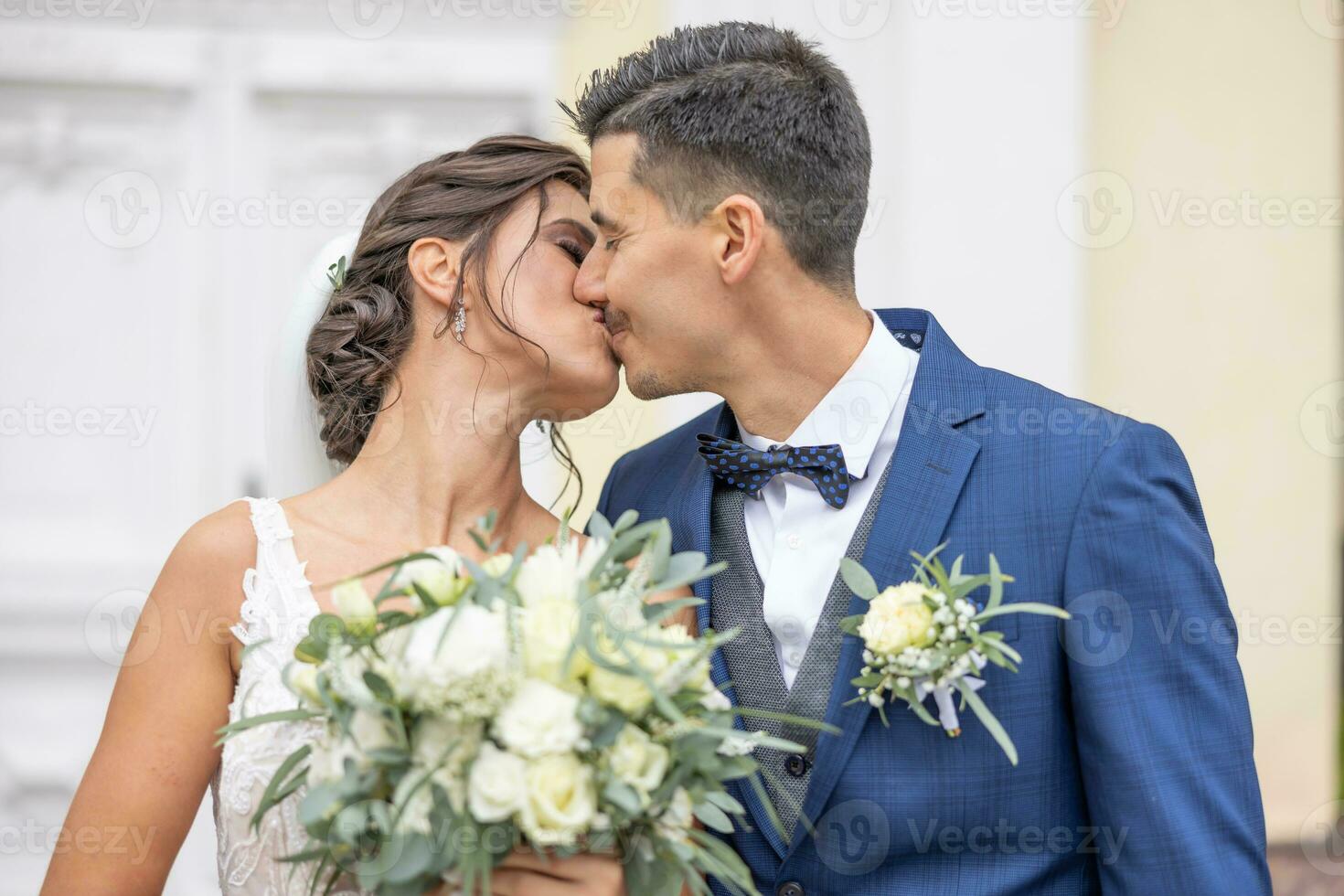 Newlywed husband and wife are kissing their first kiss on their special day photo