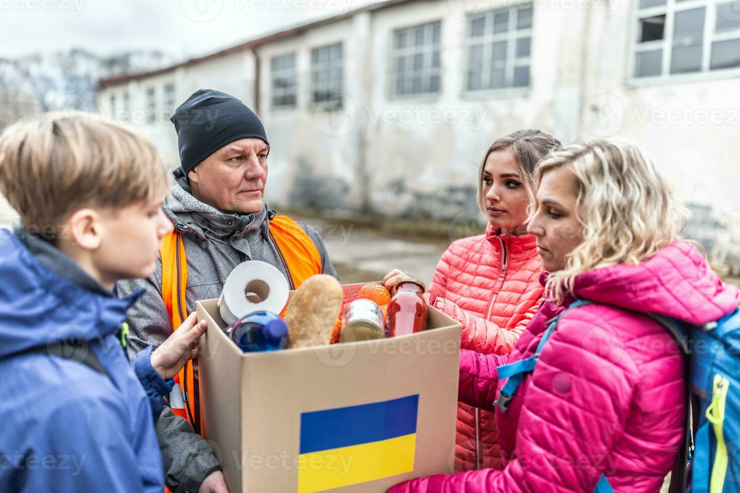 Vysne Nemecke, Slovakia. March 30. 2022. Male NGO worker gives a box of basic food and toiletries to a family of three at the border fleeing the conflict in Ukraine photo