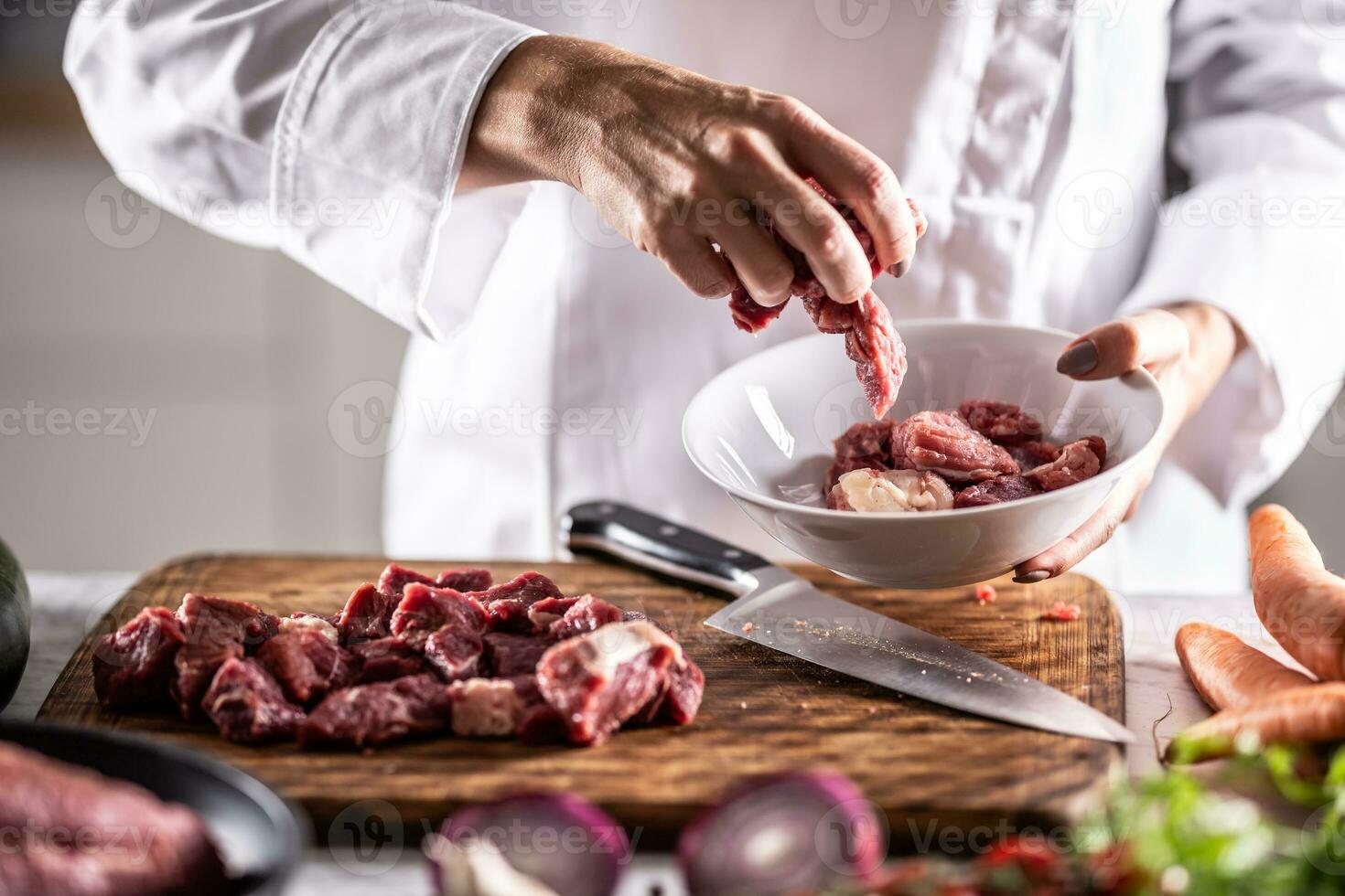 Chef puts pieces of pork into a bowl to cook it photo