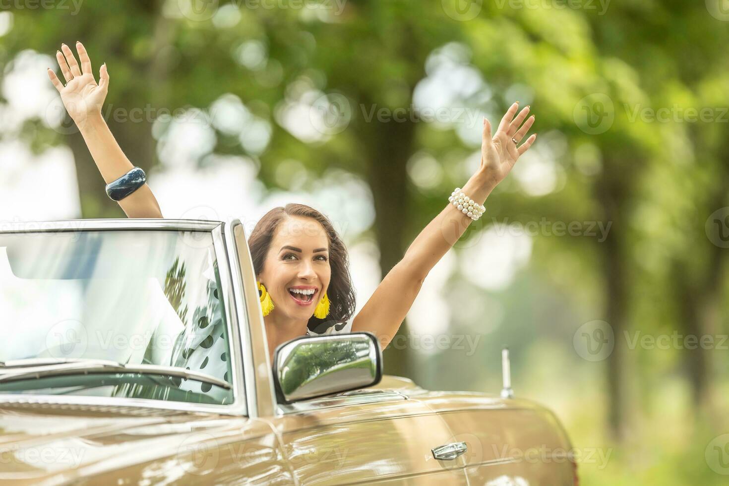 hermosa mujer en un beige convertible con brazos encima su sonriente dentro el cámara en un verano naturaleza conducir foto