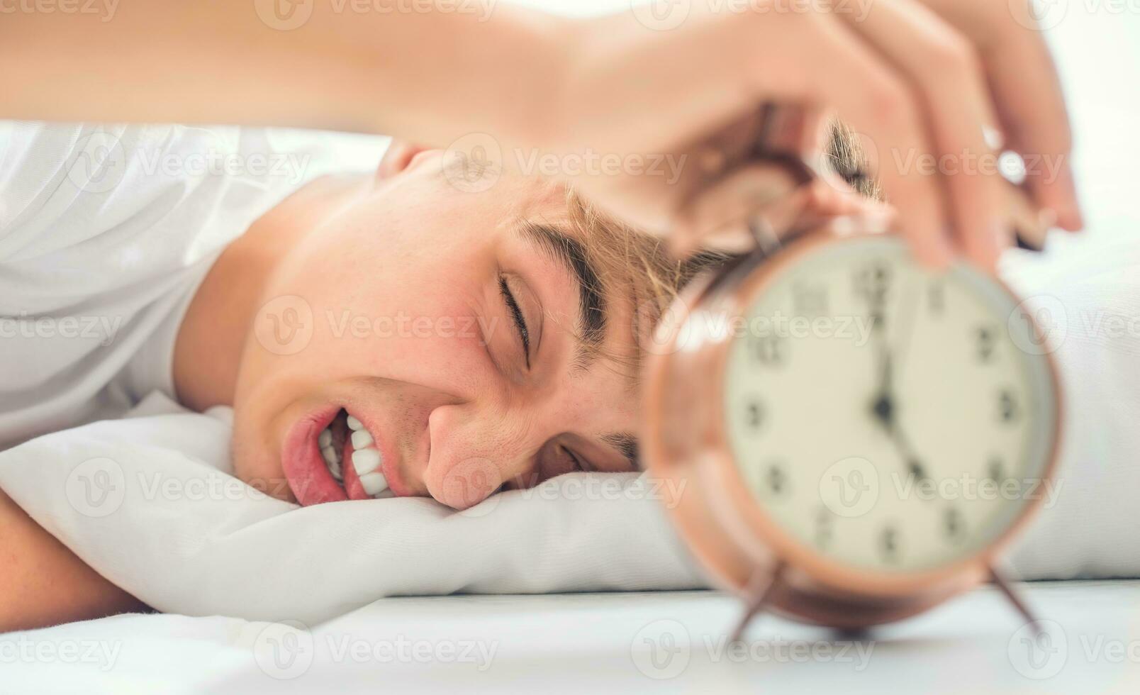 Young man is morning shocked grimace waking up alarm clock photo