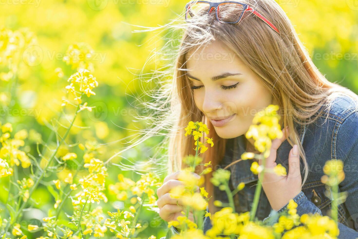 hermosa joven niña huele amarillo flores en un prado con su ojos cerrado, sonriente foto