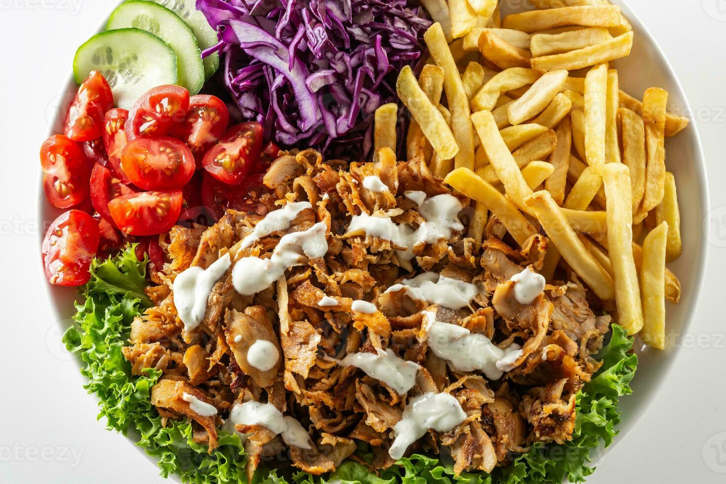 Isolated traditional Turkish chicken kebab prepared with lovely fries, fresh vegetables and yummy dressing photo