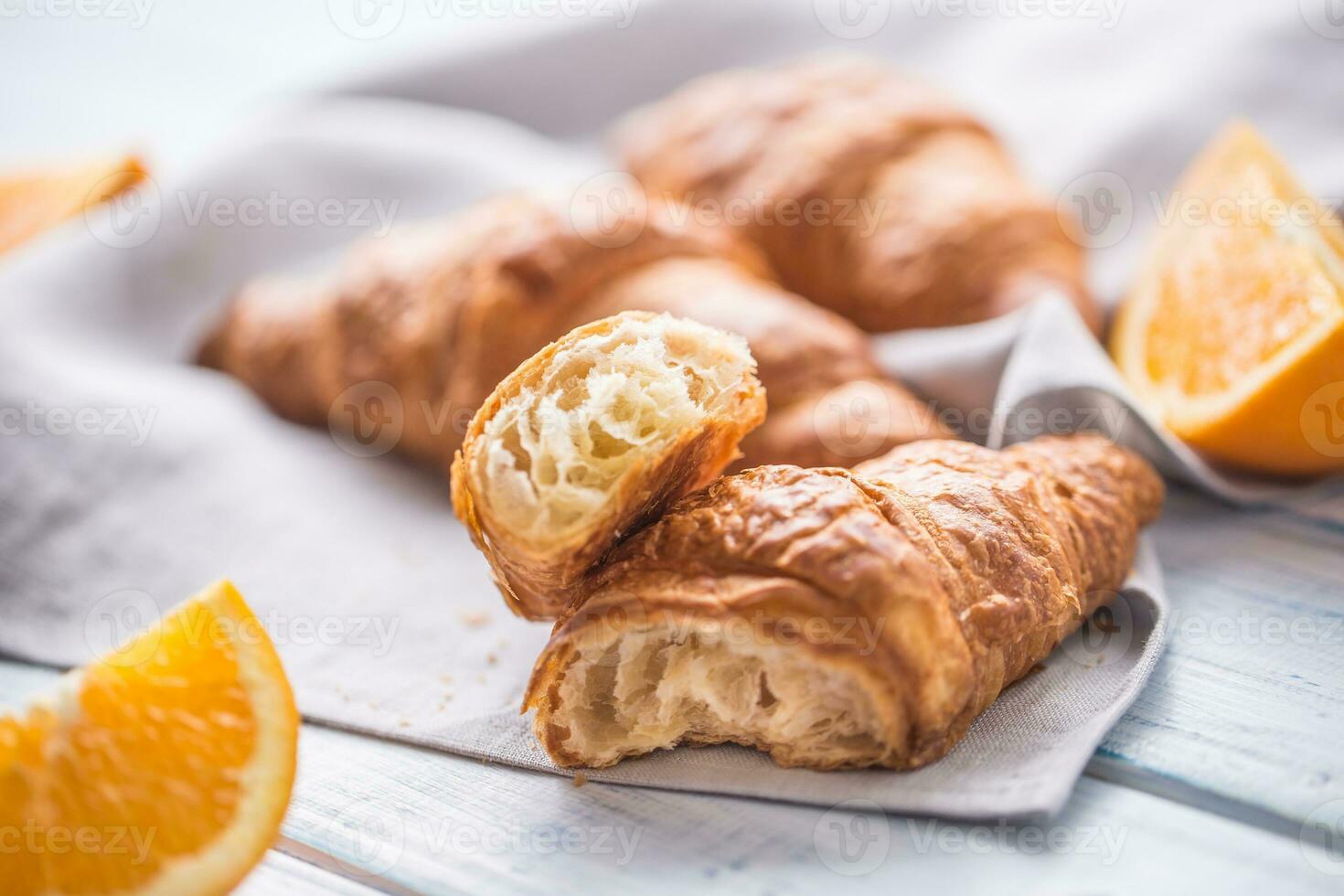 Fresco mantecoso cruasanes con dulce naranjas en cocina servilleta. foto