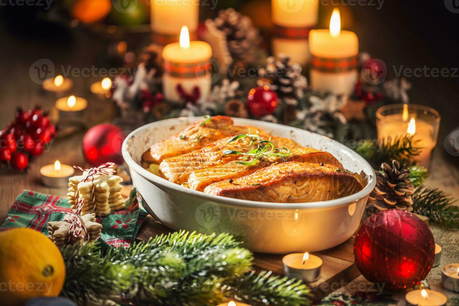 Christmas dinner from fish salmon in roasting dish with festive decoration advent wreath and candles. photo