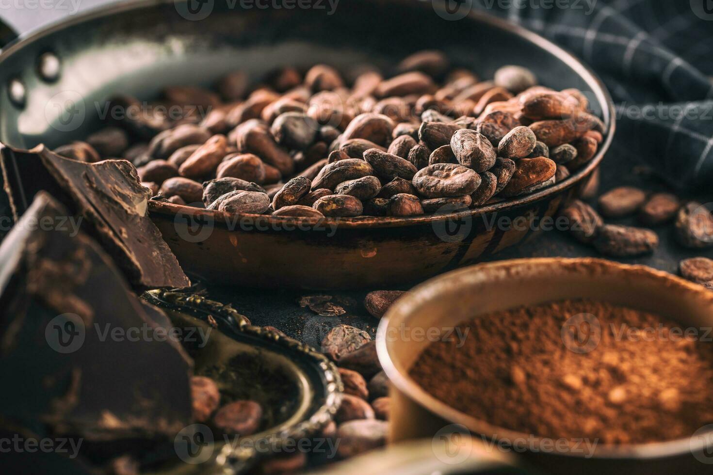 Dark chokolate cocoa beans and powder on concrete table photo